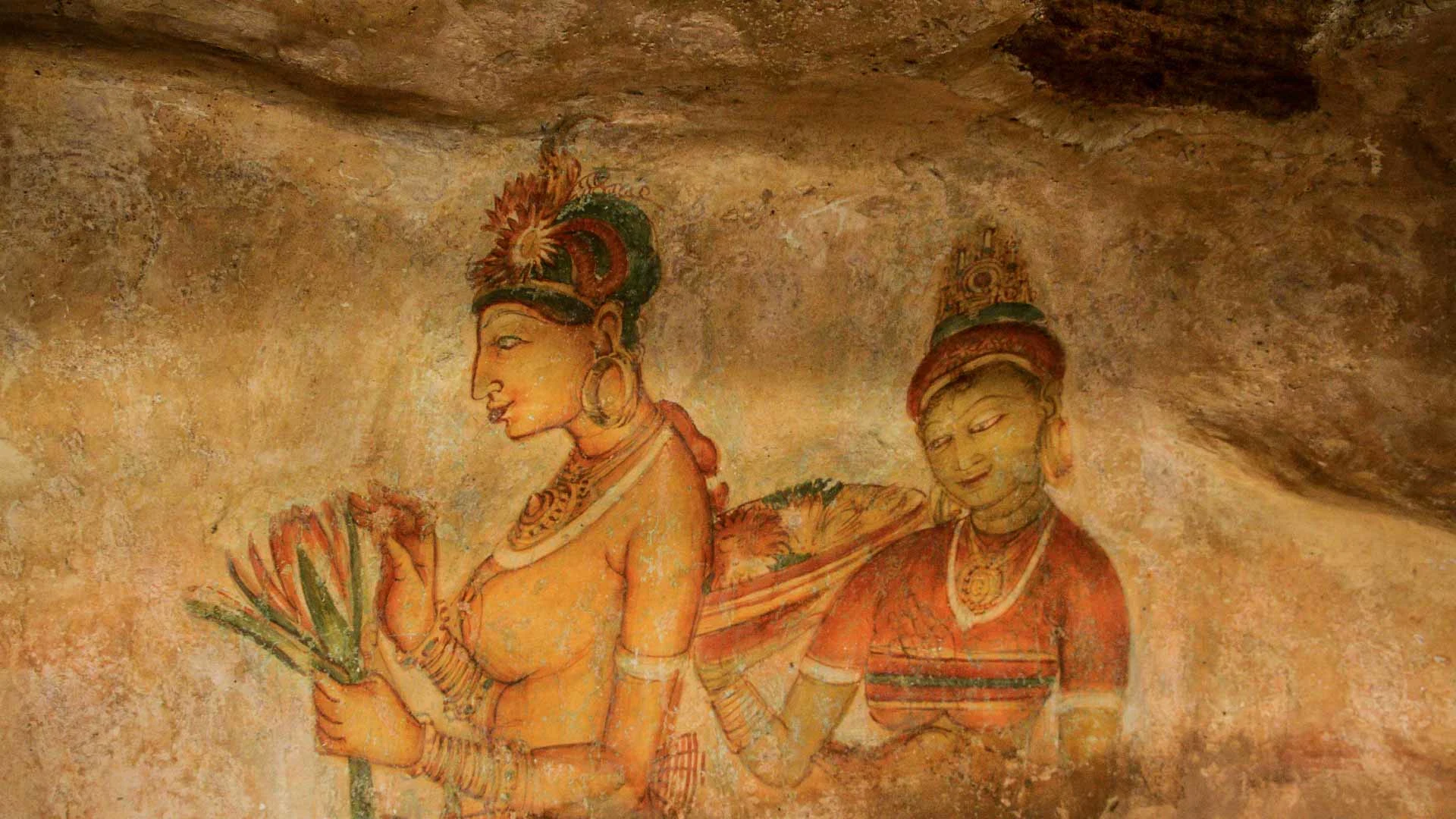 Fifth-century painted figures on the sheltered rock face halfway up Sigiriya, ochre and green against bare stone